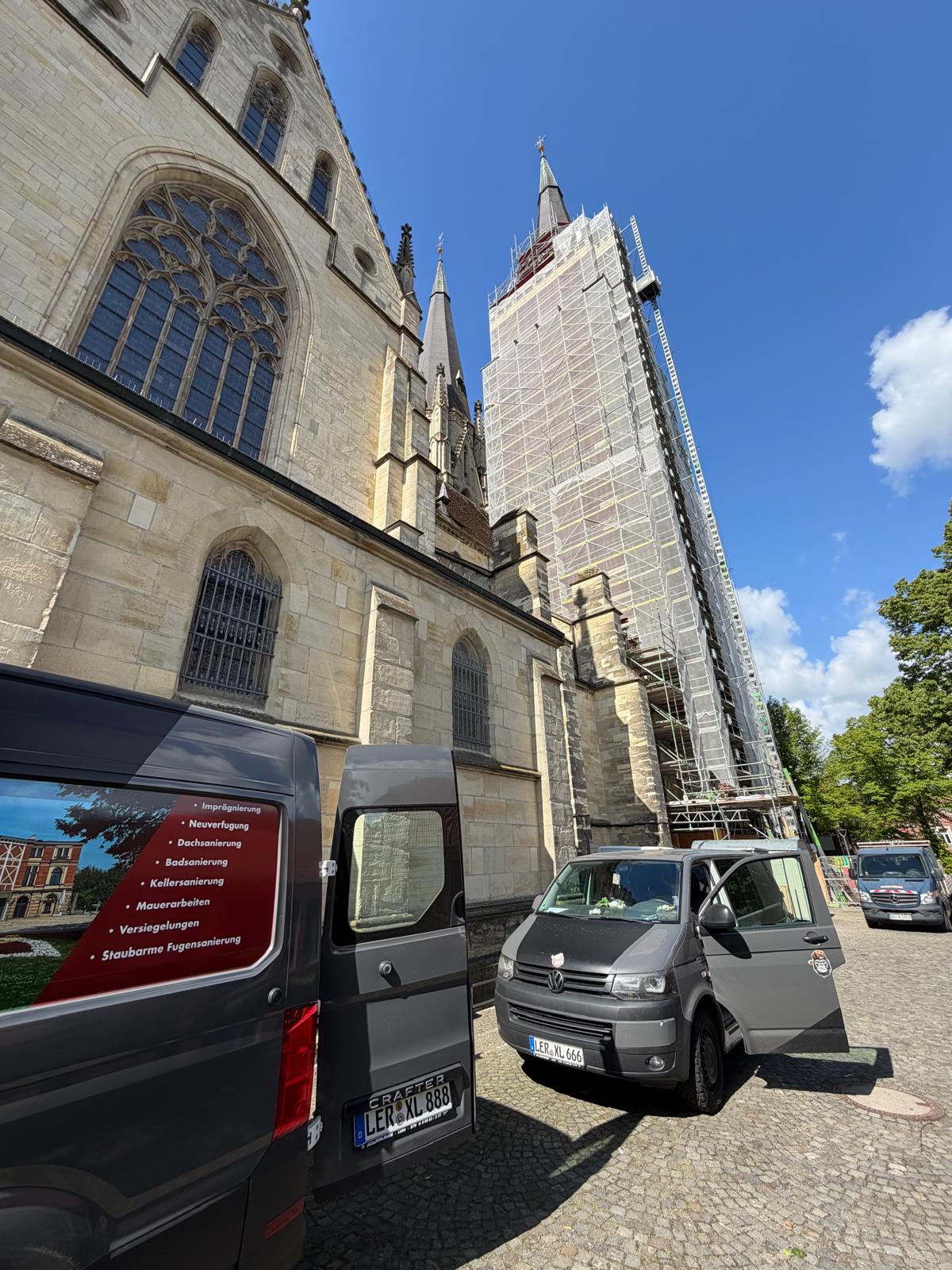 Firmenwagen von Sanierung Wilde vor einer eingerüsteten Kirche – Denkmalschutz-Restaurierung in Ostfriesland